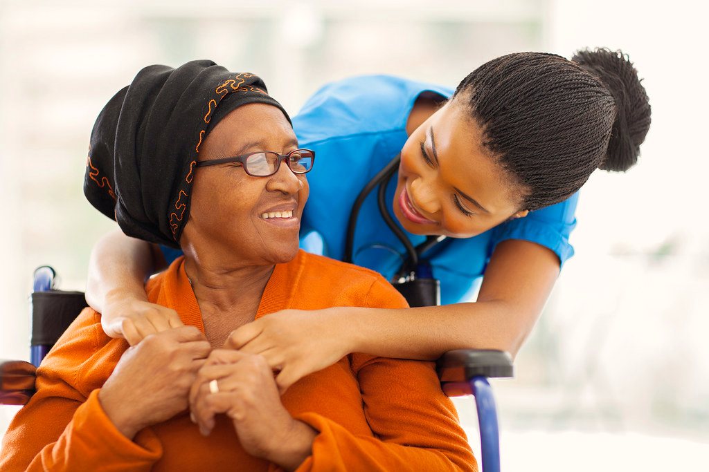 A caregiver gently holding an elderly resident's hand